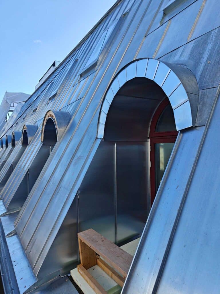 Detalj av zinktekket tak med arketak og beslag rundt takvindu i Øvre Vollgate, Oslo.